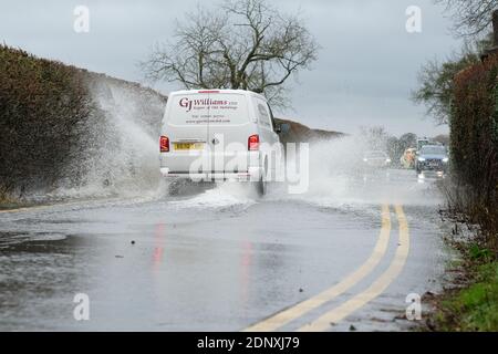 Moreton-on-Lugg, Herefordshire, UK - Friday 18th December 2020 - Vehicles drive through surface water flooding that has overspilled from the nearby River Lugg after another day of heavy rain across Herefordshire and Mid Wales. In Herefordshire both the River Wye and the River Lugg remain on Flood Alert and are exprected to rise. Photo Steven May / Alamy Live News Stock Photo