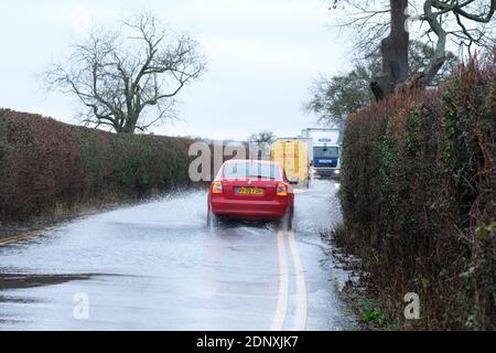 Moreton-on-Lugg, Herefordshire, UK - Friday 18th December 2020 - Vehicles drive through surface water flooding that has overspilled from the nearby River Lugg after another day of heavy rain across Herefordshire and Mid Wales. In Herefordshire both the River Wye and the River Lugg remain on Flood Alert and are exprected to rise. Photo Steven May / Alamy Live News Stock Photo