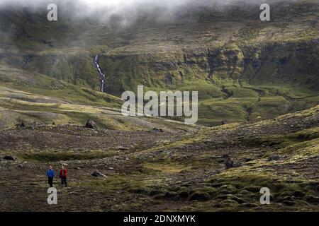 Deux femmes qui font de la randonnée en Islande. La magnifique randonnée vous mène à la plage et aux falaises près de Breidavik, en Islande de l'est. Banque D'Images