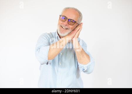 Homme de haut niveau portant une chemise décontractée dormant fatigué rêvant et posant avec les mains ensemble tout en souriant avec les yeux ouverts. Banque D'Images