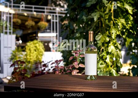 Boisson, alcool - bouteille de vin sur une table en bois de la terrasse du restaurant. Étiquette vierge pour votre texte ou logo. Maquette Banque D'Images