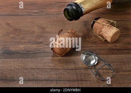 Photo en grand angle d'une bouteille de champagne ouverte avec des bouchons sur une table en bois avec espace de copie. Banque D'Images