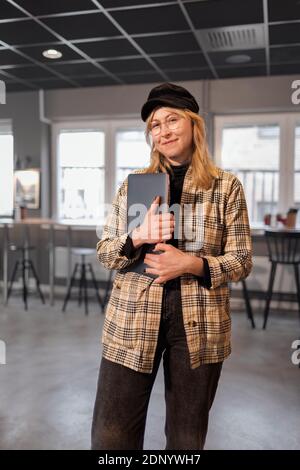 Femme souriante au bureau et regardant l'appareil photo Banque D'Images