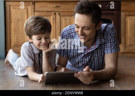 Les frères plus âgés et plus jeunes jouent au jeu vidéo à la maison à l'aide d'une tablette Banque D'Images