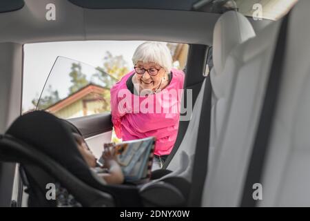 Grand-mère regardant la petite fille assise dans la voiture Banque D'Images