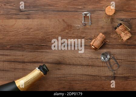 Photo en grand angle d'une bouteille de champagne avec des bouchons dans les coins opposés du cadre, sur une table en bois avec espace de copie. Banque D'Images