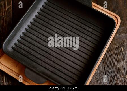 Nouveau gril vide en fonte avec deux poignées sur fond en bois. Placez pour le texte. Flat Lay Top vue de dessus poêle en fonte noire pour barbecue. Maquette alimentaire Banque D'Images