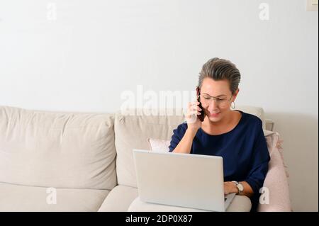 Woman on sofa talking via cell phone Stock Photo