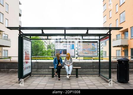 Des amies attendent à l'arrêt de bus Banque D'Images