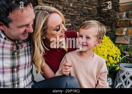 Bonne famille assise sur le porche souriant et riant Banque D'Images