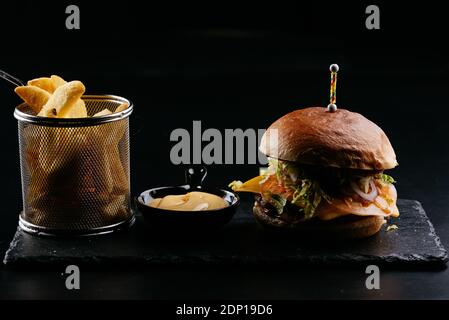 Burger, potatoes, sauce on a black background Stock Photo