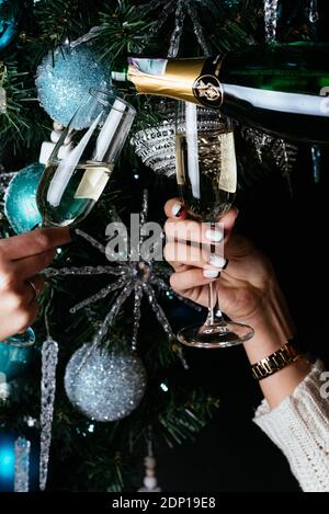 mains de femmes tenant des verres de champagne sur le fond d'un arbre de noël Banque D'Images