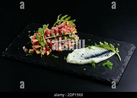 salmon tartare with white sauce on a black background Stock Photo