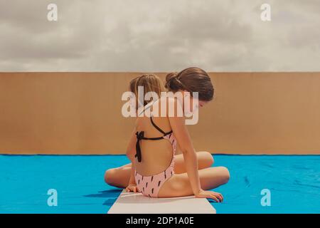 Deux filles jouant à la piscine sur la terrasse du toit Banque D'Images