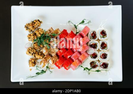 Sushi japonais sur une assiette blanche et un fond noir Banque D'Images