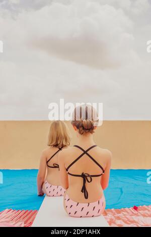 Vue arrière de deux filles jouant à la piscine sur la terrasse du toit Banque D'Images