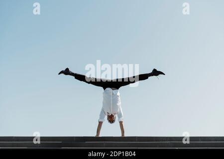 Businessman doing a handstand sur haut des escaliers Banque D'Images