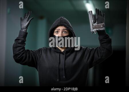 Voleur a cassé dans l'appartement. Cambriolage de maison par femme dans une veste noire et masque noir pistolet noir et crowbar. Banque D'Images