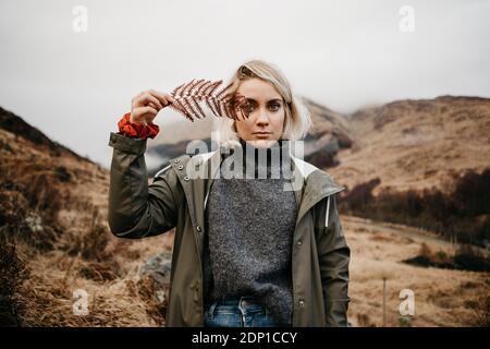 Royaume-uni, Ecosse, Highland, portrait of young woman holding fern Banque D'Images