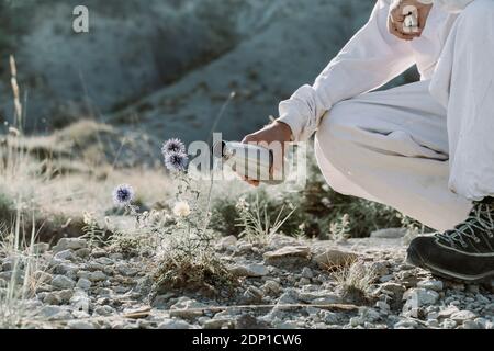 Homme arrosoir plante avec thermos flacon dans un paysage aride Banque D'Images