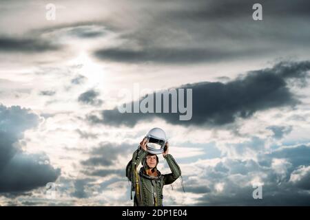 Homme posant habillé comme un astronaute sur une prairie avec des nuages dans l'arrière-plan Banque D'Images