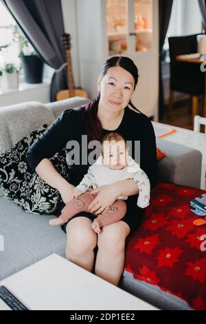 Femme assise avec bébé sur un canapé Banque D'Images