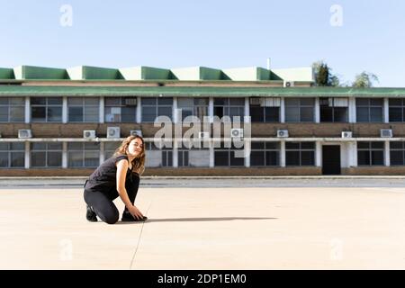 Portrait of teenage girl crouching outdoors Banque D'Images