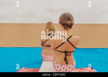 Vue arrière de deux filles jouant à la piscine sur la terrasse du toit Banque D'Images