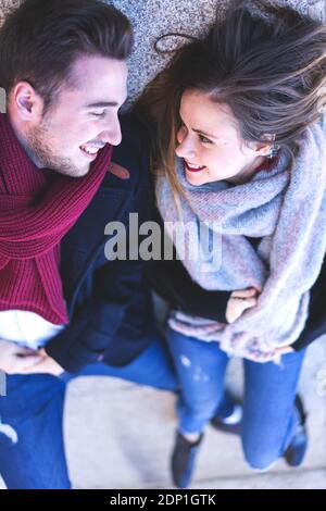 Femme et homme couché sur le sol en pierre regarder les uns les autres amoureux et souriants l'hiver Banque D'Images