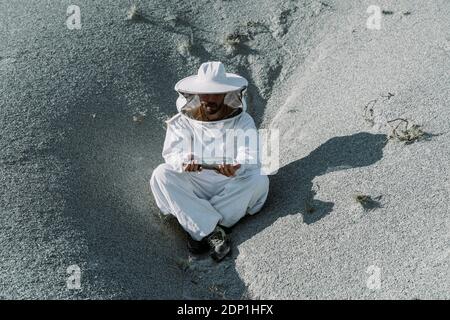 Homme portant une robe de gardien de but assis dans une apocalyptique sèche flacon thermos paysagiste Banque D'Images