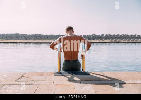 Jeune homme d'entrer dans l'eau de la jetée Banque D'Images