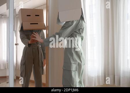 Femme portant une cardbox sur la tête avec une émoticône ennuyé se touchant miroir Banque D'Images