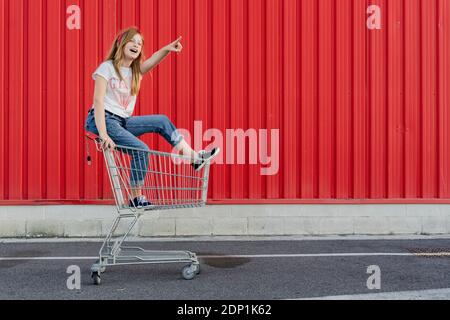 Fille dans un panier à l'avant du mur rouge Banque D'Images