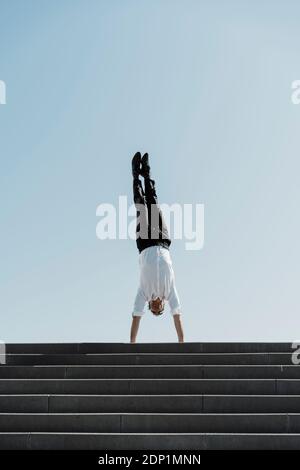 Businessman doing a handstand sur haut des escaliers Banque D'Images