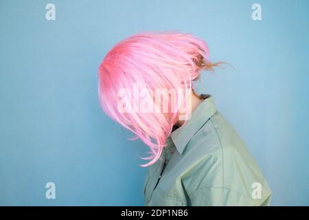 Jeune femme portant une perruque rose et regardant vers le bas Banque D'Images