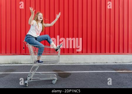 Fille dans un panier à l'avant du mur rouge Banque D'Images