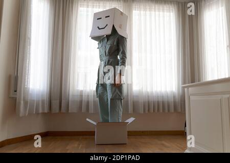 Femme portant une cardbox sur la tête avec smiley ennuyé et debout dans la boîte Banque D'Images