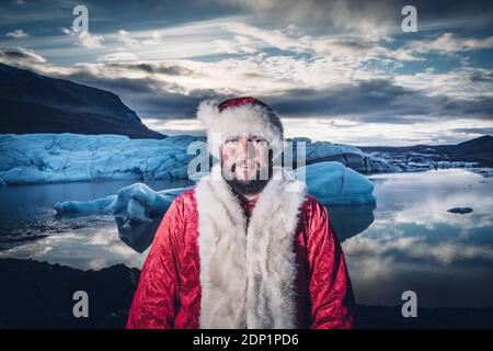 L'Islande, Portrait of a smiling man déguisé en Père Noël debout à un glacier Banque D'Images