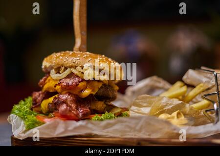 Délicieux hamburger avec double côtelette et frites sur un planche en bois Banque D'Images