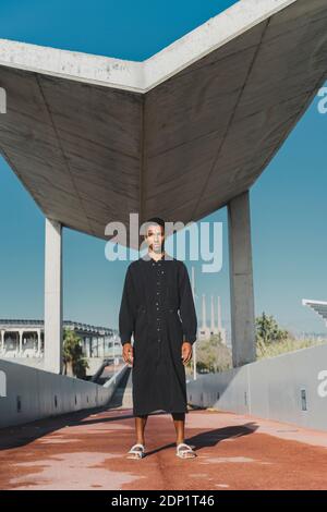 Jeune homme portant un caftan noir debout sur un pont de pied Banque D'Images