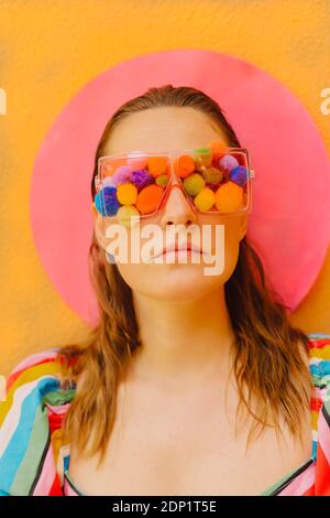 Portrait d'une femme portant des lunettes avec pompons colorés couvrant ses yeux Banque D'Images