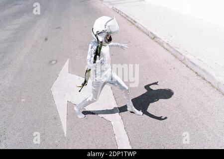 Garçon portant le costume d'astronaute marchant sur la route en ville Banque D'Images