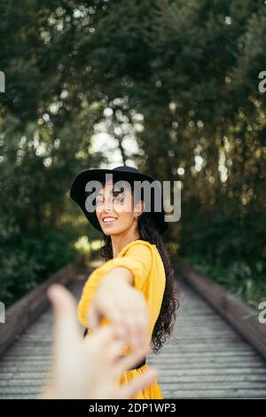 Jeune femme portant un chapeau noir et jaune robe et tenant une part Banque D'Images