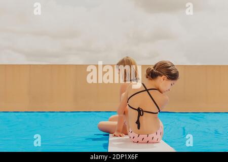 Vue arrière de deux filles jouant à la piscine sur la terrasse du toit Banque D'Images