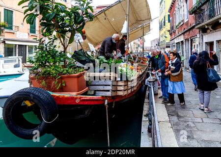 Les gens de la région achètent des fruits et des légumes frais à une Péniche mobile dans le quartier Castello de Venise, Venise, Italie. Banque D'Images