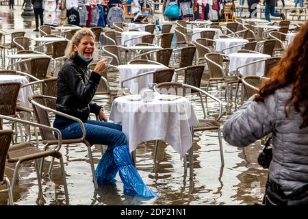 Une femme buvant du thé dans UN café de la place Saint-Marc pendant l'Acqua Alta (High Tide), Venise, Italie. Banque D'Images