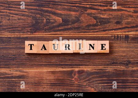 Lettrage mot taurine en cubes de bois sur fond rustique foncé en bois. La taurine aide à améliorer le métabolisme énergétique dans le corps. Foo de culturisme Banque D'Images
