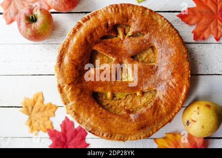 Délicieuse tarte maison pour halloween sur table en bois blanc avec pommes et feuilles d'automne Banque D'Images