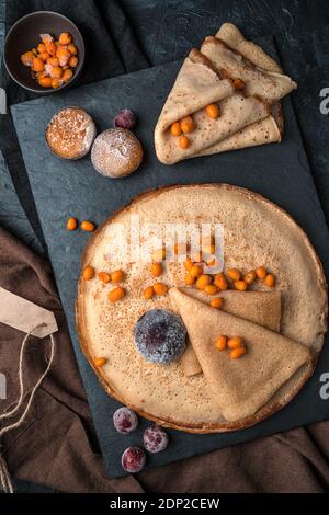 Composition culinaire avec crêpes et baies fraîches surgelées sur fond sombre. Banque D'Images