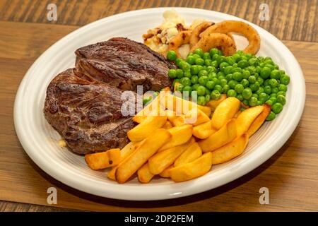 Steak Dinner - steak de bœuf, avec frites, petits pois, rondelles d'oignon et chou-fleur. Banque D'Images